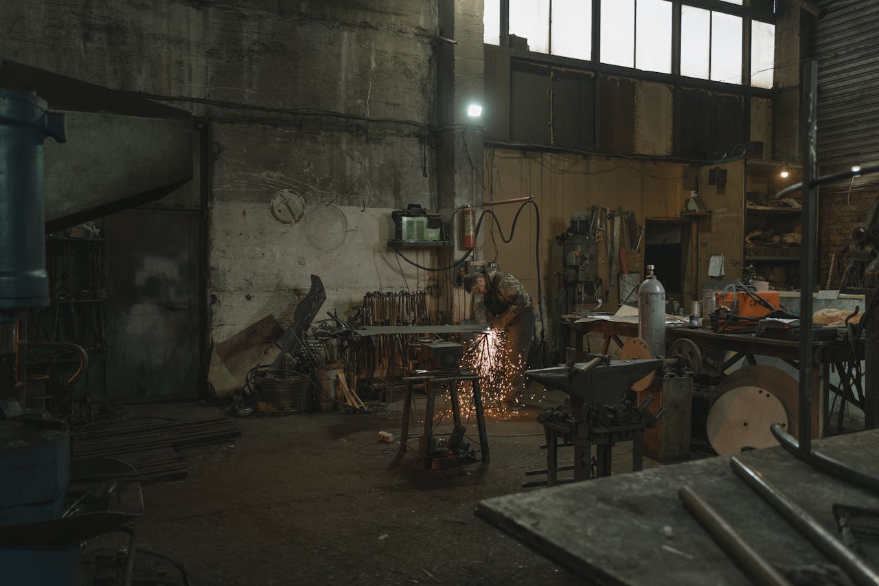 about-us A welder skillfully works with sparks flying in an industrial workshop setting.